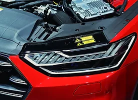 Detailed View Of The Engine Bay In A Red Audi, Highlighting The Engine And Surrounding Mechanical Parts.