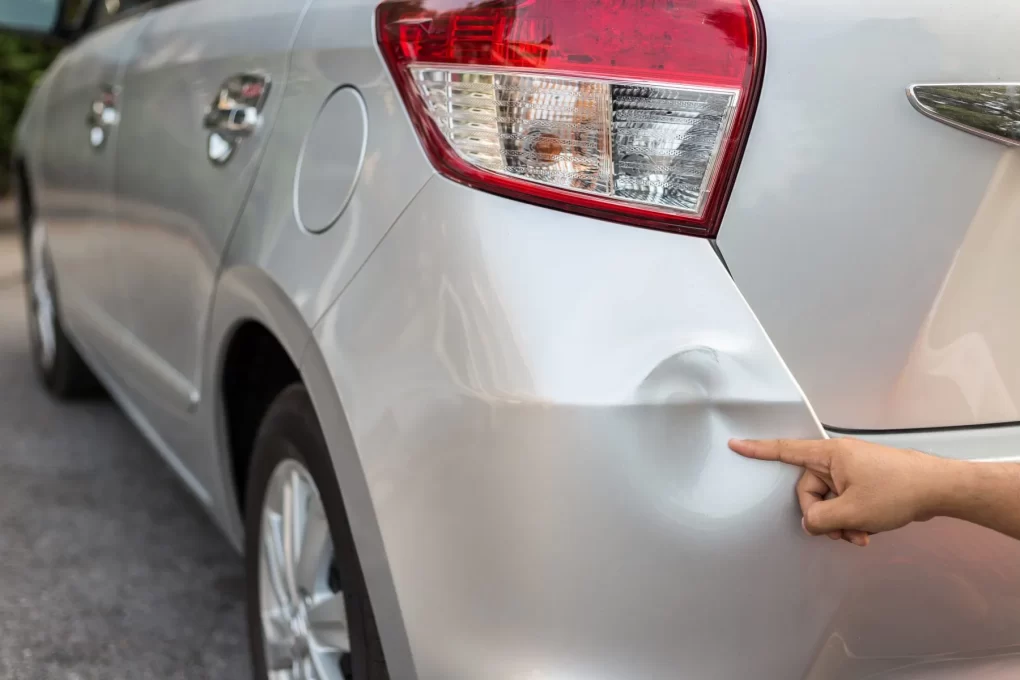 A Man In London Motor Sports Car Pointing Toward A Silver Car With Dent Repair And Showing To Take Car Dent Repair Service