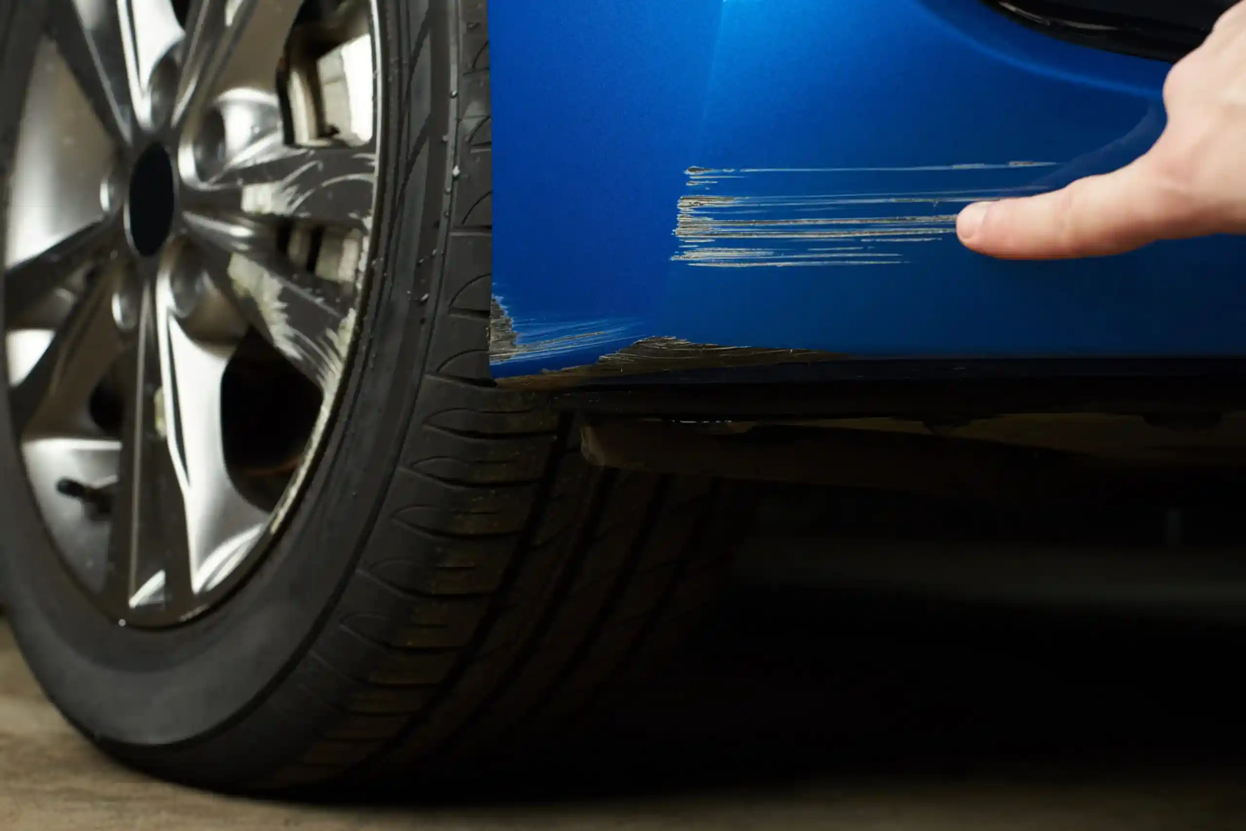 A Man Pointing Through His Finger Showing A Blue Car With Car Scratch Repair By London Motor Sports