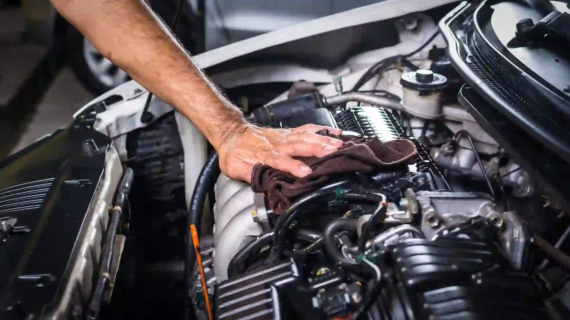 A Man Cleainging Engine Through Cloth Showing That It Require Fuel System Repair