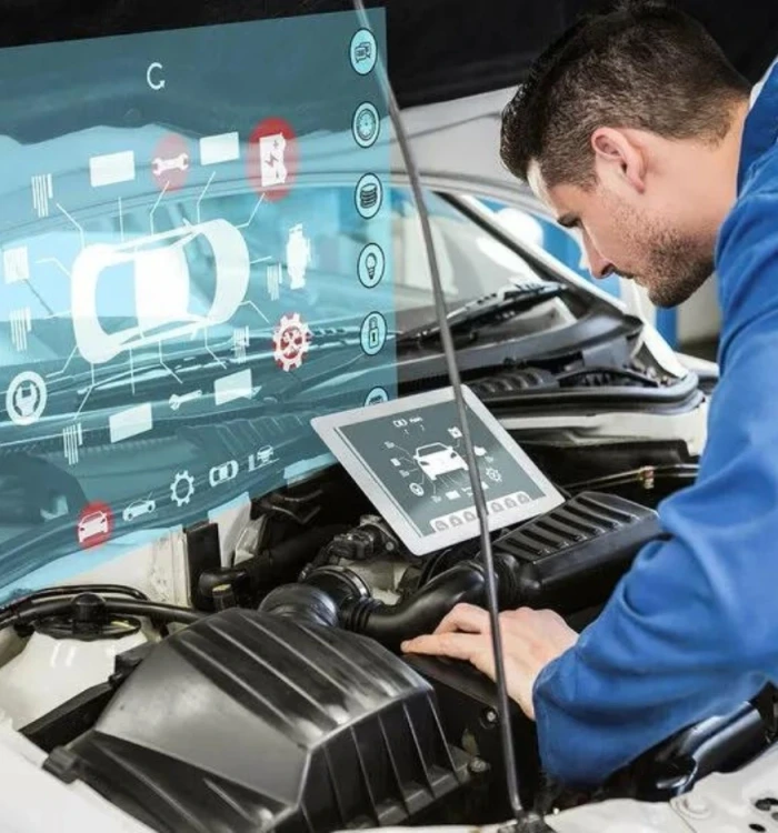 A Man Diligently Repairs A Car Engine, Focused On His Task With Tools In Hand And Parts Spread Around Him.